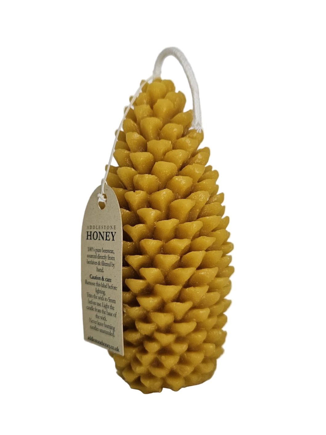 Pine cone-shaped beeswax candle with a branded instructions tag on a white background
