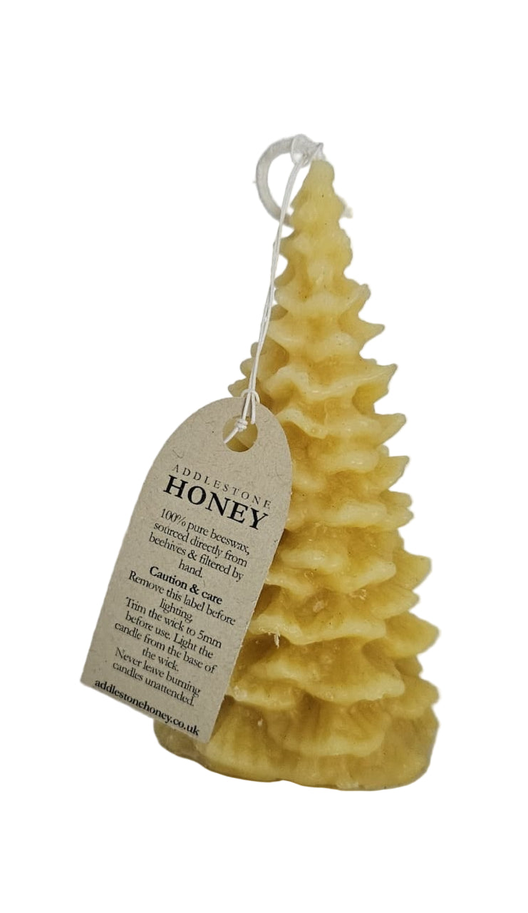 Yellow fir tree beeswax candle with a tag on a white background