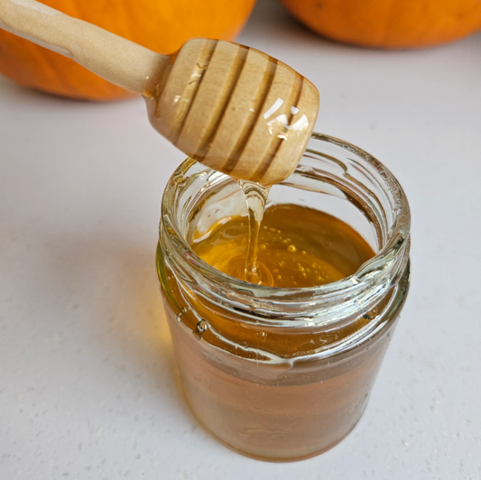 A honey dipper in a jar of real honey.