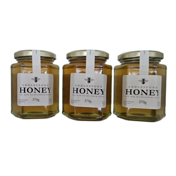 Three glass jars of Raw Addlestone Honey with white labels.