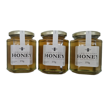 Three glass jars of Raw Addlestone Honey with white labels.